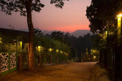 una strada vuota con luci su una recinzione al tramonto di Amrezy Resort and Spa by Stride, Wayanad a Vythiri