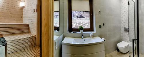 a bathroom with a sink and a toilet and a window at Dom Pod Leśniczówką in Zachełmie