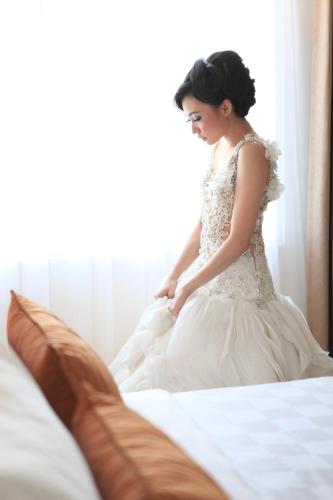 a woman in a wedding dress sitting on a bed at Swiss-Belinn Manyar in Surabaya