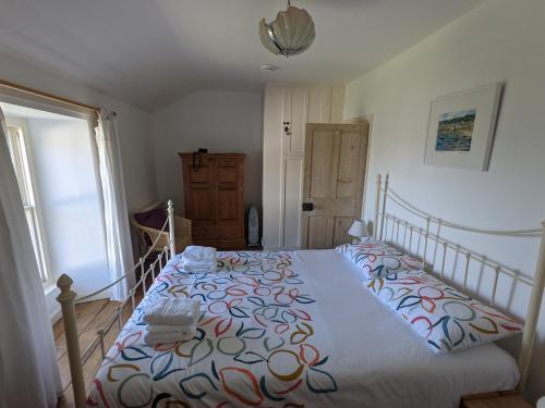ein Schlafzimmer mit einem Bett mit einer farbenfrohen Tagesdecke in der Unterkunft Traditional Fisherman's Cottage with 3 bedrooms in Mousehole