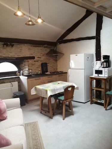 a kitchen with a table and a white refrigerator at Le Courtil mezzanine in Dohan