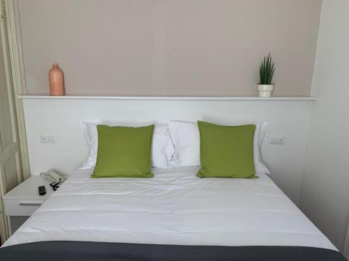 a white bed with two green pillows on it at Hotel Loveno in Menaggio