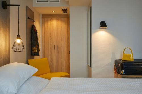 a bedroom with a bed and a yellow chair at Hotel Concorde in Munich
