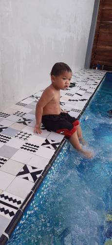 a young boy sitting on the edge of a swimming pool at Origin hua hin poolvilla in Hua Hin