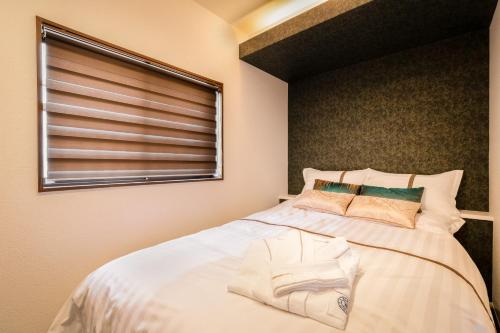 um quarto com uma grande cama branca com janela em Hotel kiki em Osaka