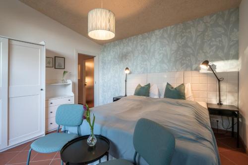 a bedroom with a bed and two blue chairs at Schloss-Castel Pienzenau - Guestrooms & Apartments - B&B-Hotel & Restaurant in Merano