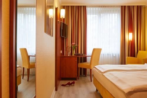 a hotel room with a bed and a table and chairs at Hotel Concorde in Munich