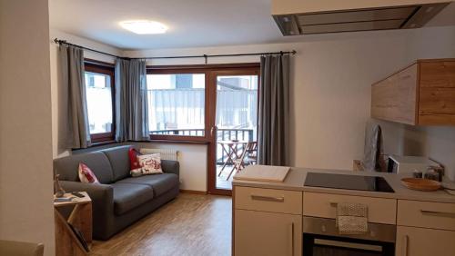 ein Wohnzimmer mit einem Sofa und einer Küche in der Unterkunft CasaViva - Grazioso bilocale all’Alpe di Siusi in Kastelruth