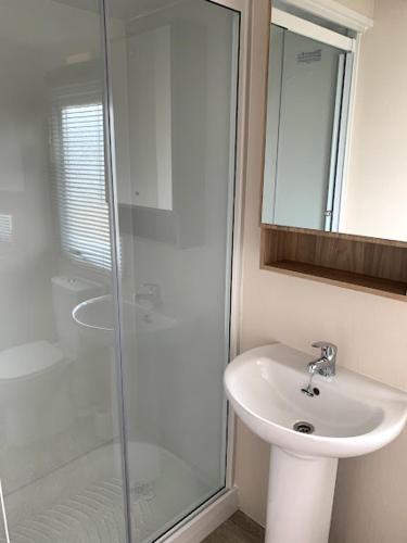 a bathroom with a sink and a glass shower at Lovely 4 berth caravan on 7 Lakes Country Park at Crowle North Lincolshire in Crowle