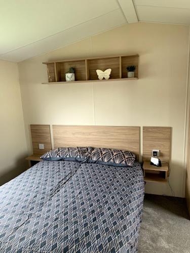 a bedroom with a bed with a blue comforter at Lovely 4 berth caravan on 7 Lakes Country Park at Crowle North Lincolshire in Crowle