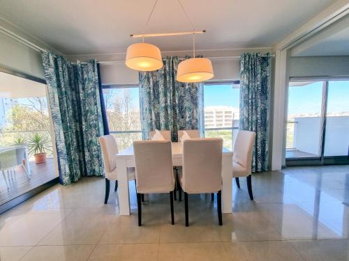 a dining room with a table and chairs and windows at Foz Palace Spa Luxury Residence in Portimão