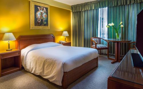 a hotel room with a large bed and a desk at Qarmenqa Hotel in Cusco