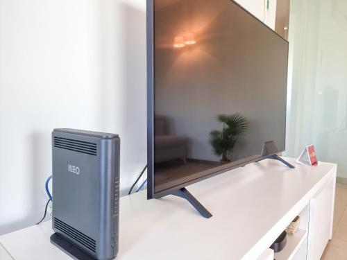 a computer monitor on a white table with a mirror at Foz Palace Spa Luxury Residence in Portimão