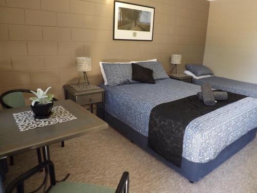 1 dormitorio con 2 camas, mesa y sidx sidx sidx de mesa en Sunbird Motel en Townsville