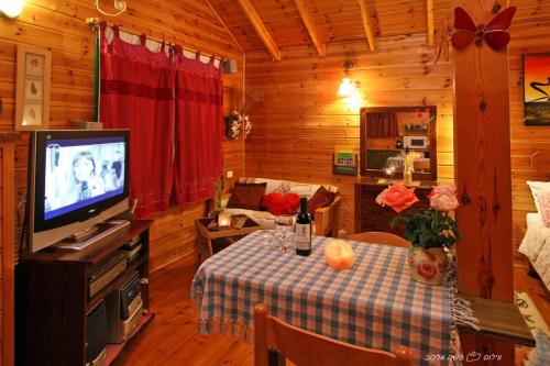 a living room with a table and a television at בקתות מול השקיעה in Wadi Keren