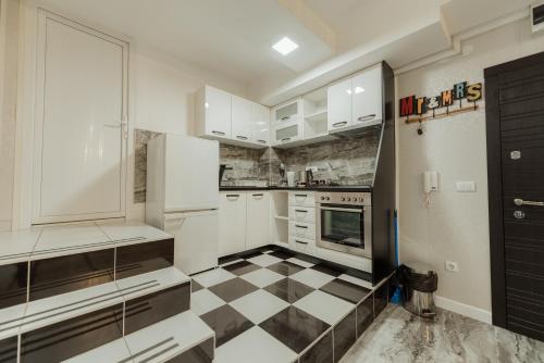 a kitchen with white cabinets and a black and white checkered floor at Spa Lux Apartmani in Novi Sad