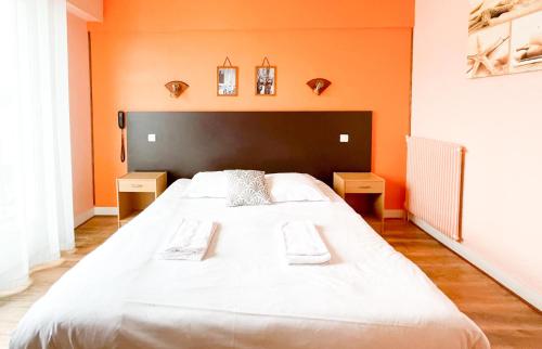 a large white bed in a room with orange walls at Hotel les Alignements in Carnac