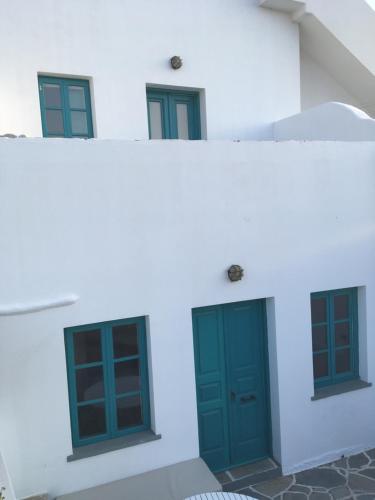 a white building with green doors and windows at Kifines Suites in Chora Folegandros