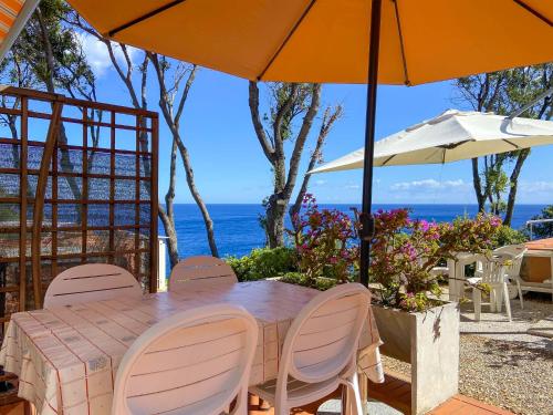 a table with chairs and an umbrella and the ocean at Residence Intur in Marciana Marina
