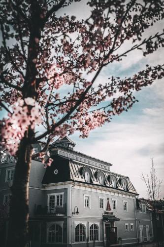 a white building with a tree in front of it at Åtellet Hotell in Norrtälje