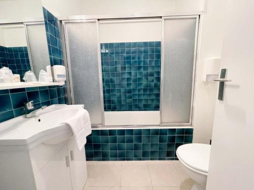 a bathroom with a sink and a toilet and blue tiles at Hotel les Alignements in Carnac