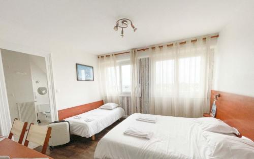 a hotel room with two beds and a mirror at Hotel les Alignements in Carnac