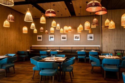 um restaurante com mesas, cadeiras azuis e luzes em Wyndham Wenzhou Cangnan Resort em Yuliao