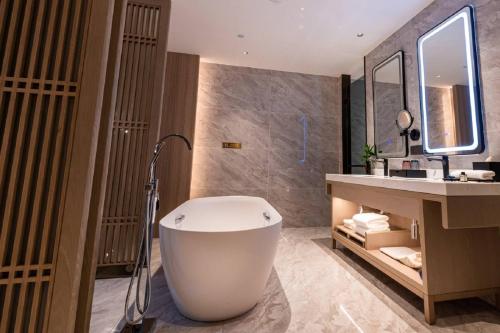 a bathroom with a bath tub and a sink at Wyndham Wenzhou Cangnan Resort in Yuliao