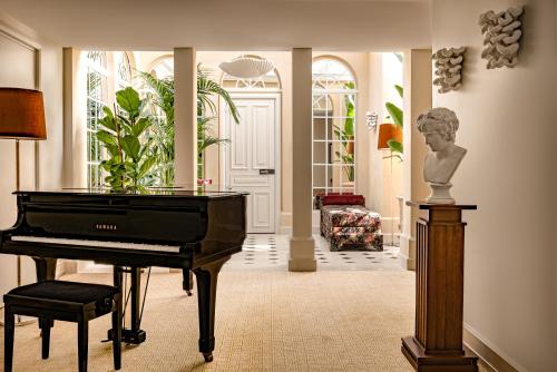 a living room with a piano and a bust on a table at Saint James Paris in Paris