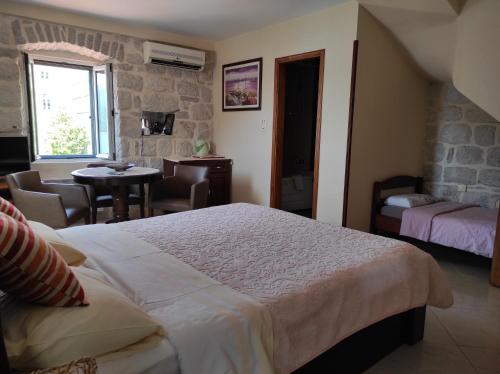 a bedroom with a bed and a table and a window at Gudelj Apartments in Perast