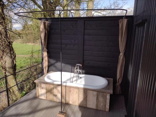The Water Shack - Amazing tiny house retreat في وودبريدج: حمام مع حوض على سطح خشبي
