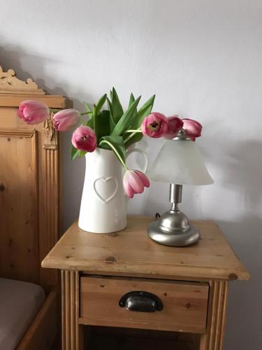 a vase of pink flowers on a table with a lamp at Pension Laura in Chřibská