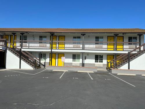 a parking lot in front of a building with yellow doors at Escondido Inn in Escondido