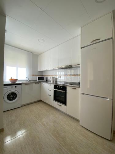 a white kitchen with a refrigerator and a dishwasher at Casa Queralt in Les Cases d'Alcanar