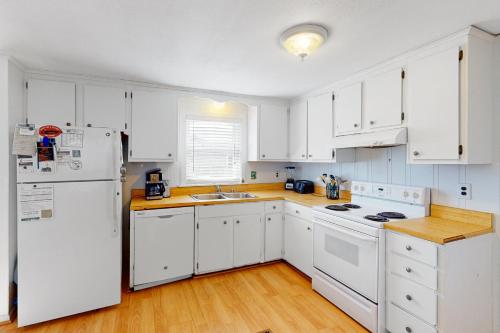 a kitchen with white cabinets and a white refrigerator at Walk the Plank 876 in Hatteras