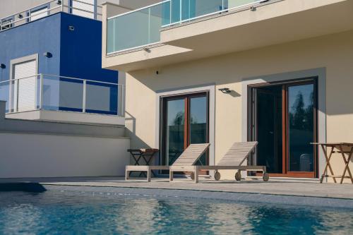 a house with two chairs next to a swimming pool at Wellnesshouse in Atouguia da Baleia