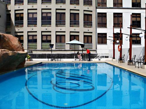 a large blue swimming pool in front of a building at Merdeka Palace Hotel & Suites in Kuching