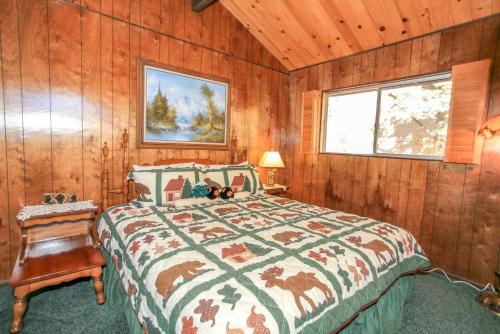 ein Schlafzimmer mit einem Bett in einem Zimmer mit Holzwänden in der Unterkunft Above it All-1685 by Big Bear Vacations in Big Bear City