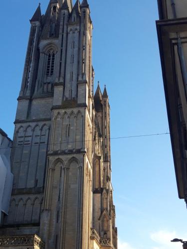 a tall tower of a cathedral with a blue sky at Agréables chambres indépendantes - Coutances centre in Coutances