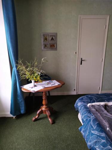 a small table in a room with a bed and a table with a plant at Chambre d hôte de la paix in La Rochefoucauld