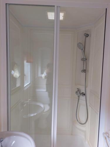 La salle de bains blanche est pourvue d'une douche et d'un lavabo. dans l'établissement Static Caravan-Field View in lovely countryside OPEN MARCH-OCTOBER, à Stratford-upon-Avon