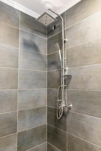 a shower in a bathroom with a tile wall at Casa Blanca Apartman in Balatonfenyves