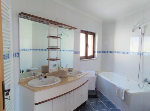 a bathroom with two sinks and a bath tub and a tubermott at Zimão Garden House in Vila Real