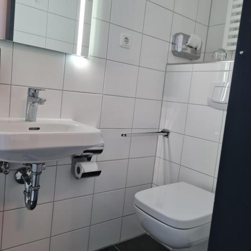 a white bathroom with a sink and a toilet at Hotel Garni Kastanjehoff in Timmel