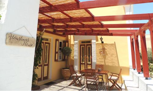 a patio with a table and chairs under a wooden pergola at Aloustina's House in Symi