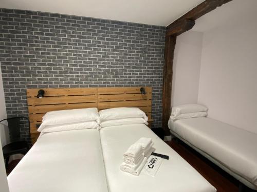 two beds in a room with a brick wall at Casual Mardones in Bilbao
