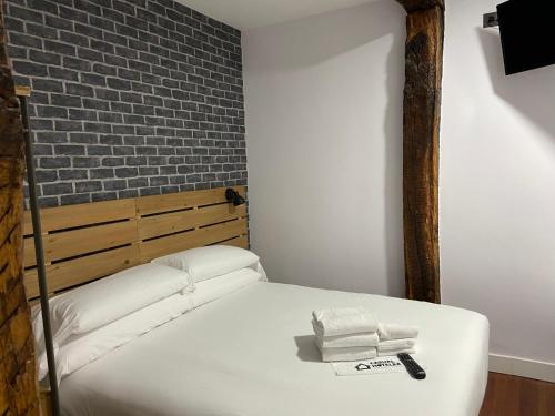 a bedroom with a bed with towels and a brick wall at Casual Mardones in Bilbao