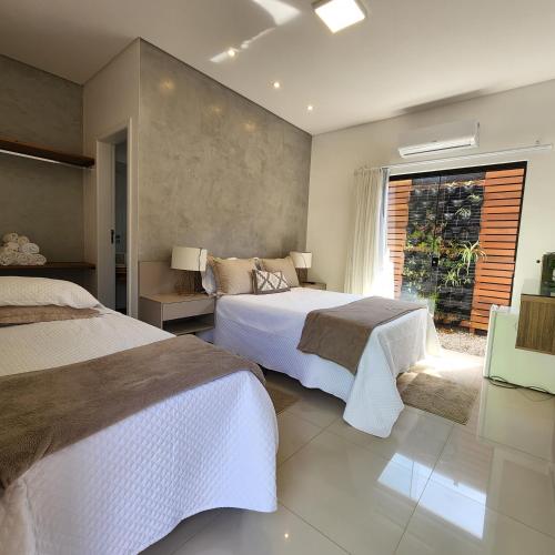 a bedroom with two beds and a window at Rei dos Mares Suítes in Ubatuba