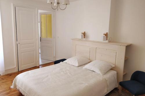 ein Schlafzimmer mit einem weißen Bett und einem blauen Stuhl in der Unterkunft Le Cheylard, appartement spacieux et lumineux in Le Cheylard