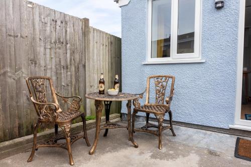 Kelston View by Cliftonvalley Apartments في بريستول: طاولة مع كرسيين وزجاجتين من النبيذ